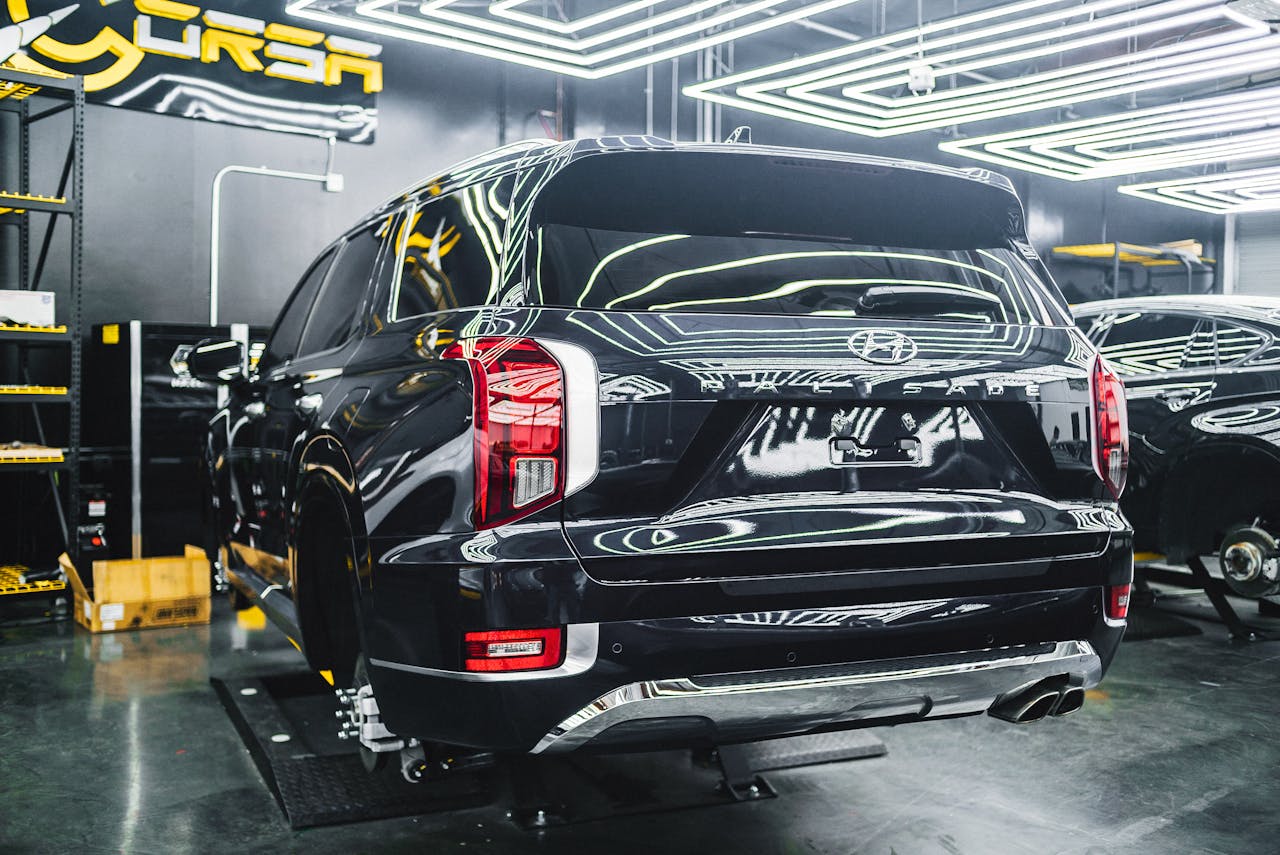 A Hyundai Palisade undergoing maintenance in a sleek, modern garage with bright lighting.